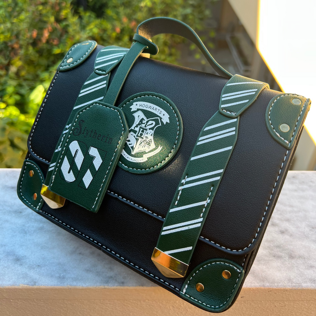 Black handbag with green accents and a logo, placed outdoors on a surface.